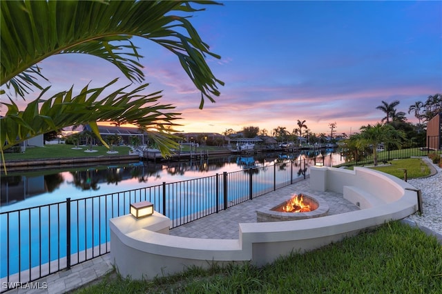 pool at dusk with a water view and a fire pit