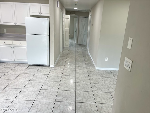 kitchen with white cabinets, light tile patterned flooring, and white refrigerator