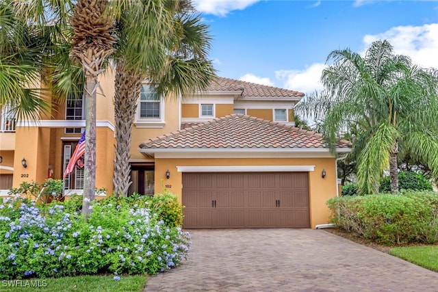 view of front facade featuring a garage, decorative driveway, a tiled roof, and stucco siding