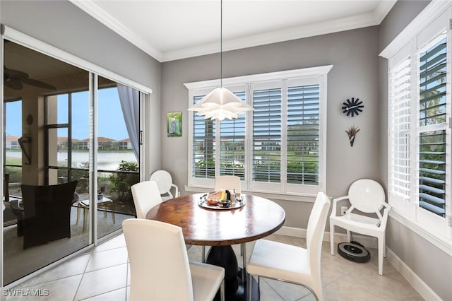 tiled dining space featuring a healthy amount of sunlight, a water view, and crown molding