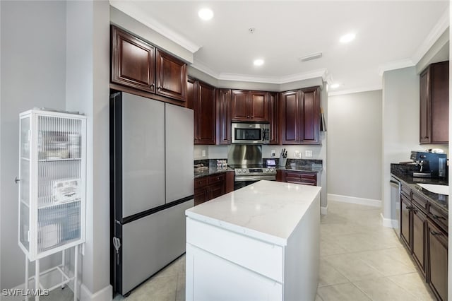 kitchen featuring appliances with stainless steel finishes, ornamental molding, dark stone counters, light tile patterned floors, and a kitchen island