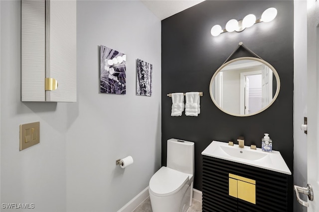 bathroom featuring baseboards, vanity, and toilet