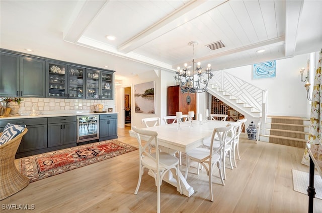 dining room featuring wine cooler, a notable chandelier, light hardwood / wood-style flooring, and bar area