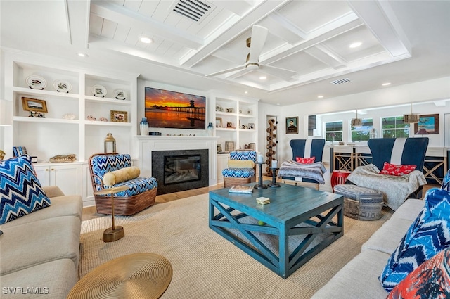 living room featuring a high end fireplace, beamed ceiling, built in features, and ceiling fan