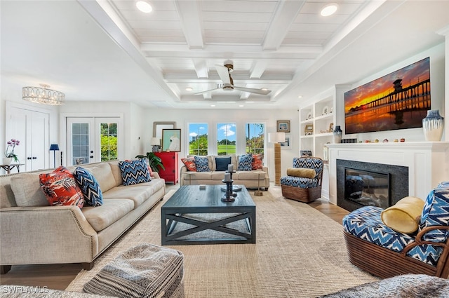 living room featuring ceiling fan, wood-type flooring, a wealth of natural light, and beamed ceiling