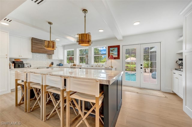 kitchen with french doors, white cabinets, light hardwood / wood-style flooring, and a kitchen island