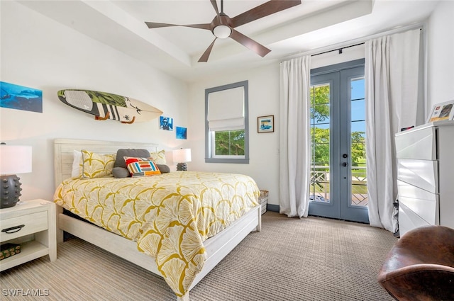 carpeted bedroom with french doors, ceiling fan, access to outside, and a tray ceiling