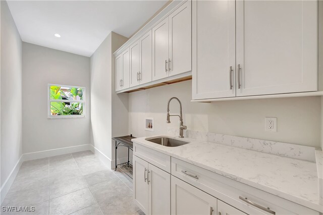 kitchen with white cabinetry, light tile patterned floors, light stone countertops, and sink