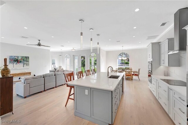 kitchen with a spacious island, sink, a breakfast bar area, decorative light fixtures, and black electric stovetop