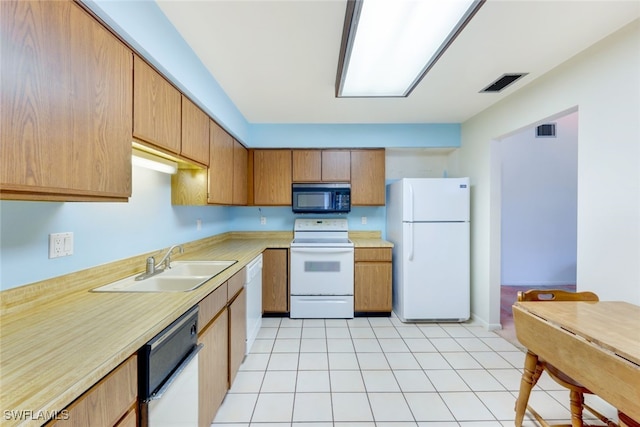 kitchen featuring white appliances, sink, and light tile patterned floors