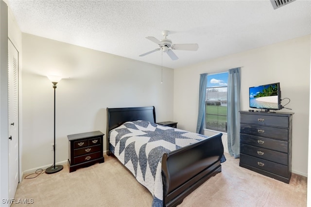 bedroom with a textured ceiling, light carpet, ceiling fan, and a closet