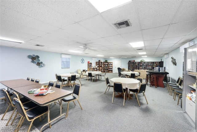 carpeted dining room with a drop ceiling and ceiling fan