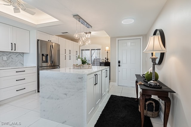 kitchen with backsplash, stainless steel refrigerator with ice dispenser, hanging light fixtures, white cabinets, and a center island