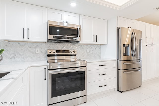 kitchen with stainless steel appliances, light tile patterned floors, crown molding, white cabinets, and decorative backsplash