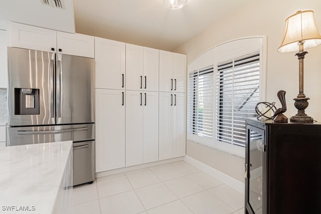 kitchen with white cabinetry, light stone countertops, light tile patterned floors, hanging light fixtures, and stainless steel fridge with ice dispenser