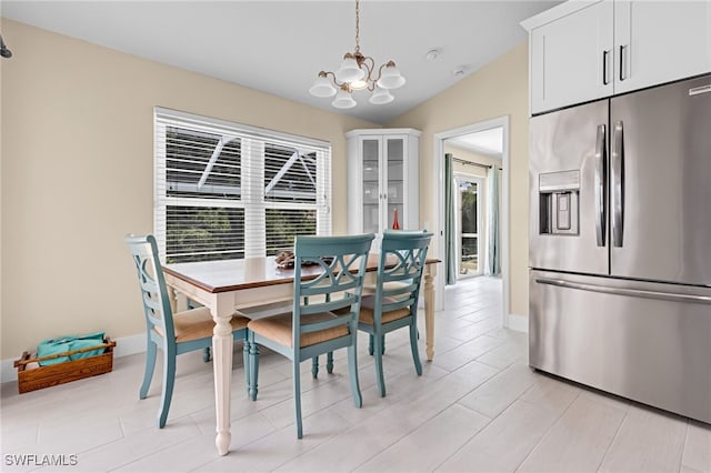 dining area with a notable chandelier, plenty of natural light, and vaulted ceiling