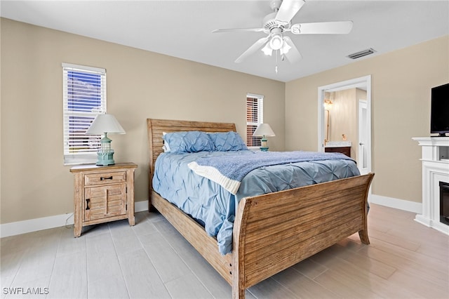 bedroom with ensuite bathroom, light wood-type flooring, and ceiling fan