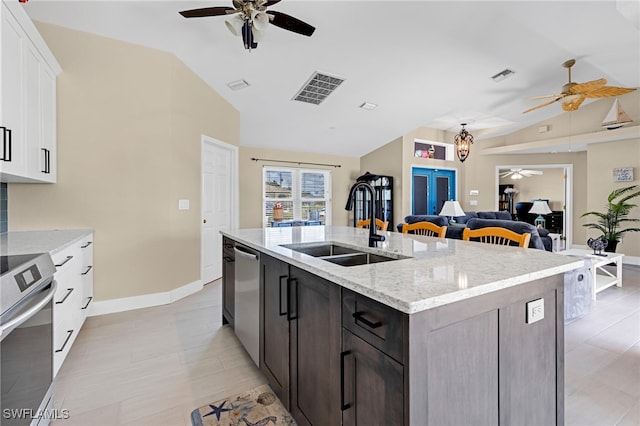 kitchen featuring stainless steel appliances, sink, light stone countertops, vaulted ceiling, and white cabinets