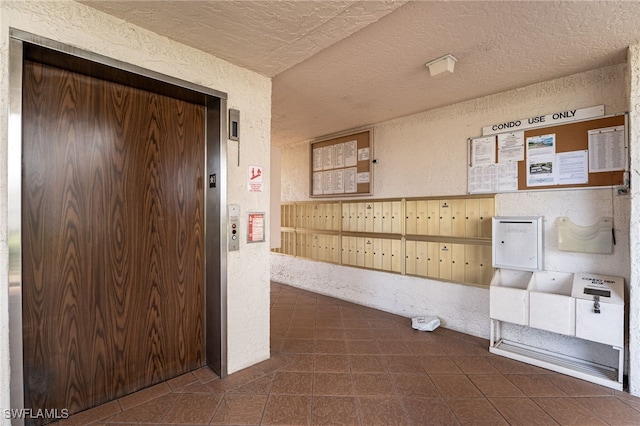 hall with elevator, mail boxes, and a textured ceiling