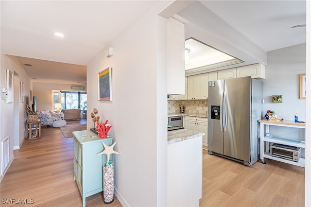 kitchen featuring light wood-type flooring, stainless steel appliances, and backsplash