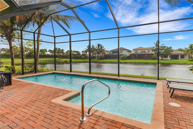 view of swimming pool featuring glass enclosure, a patio area, and a water view