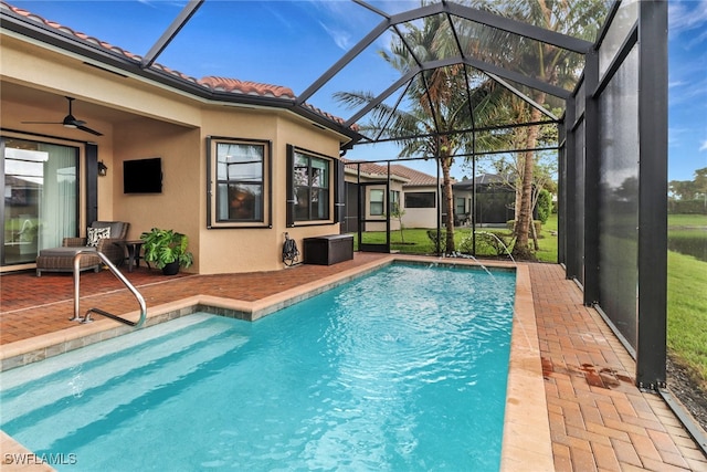 view of swimming pool with ceiling fan, glass enclosure, and a patio area