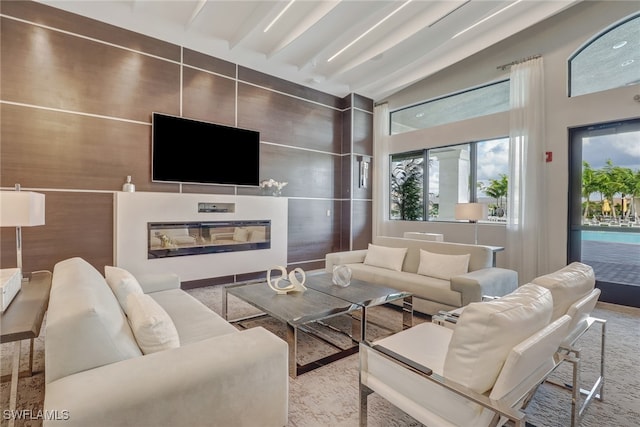 living room with light carpet, beamed ceiling, and a high ceiling