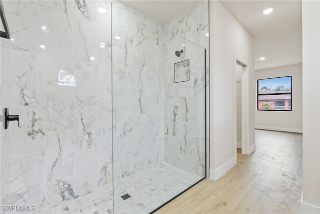 bathroom with tiled shower and hardwood / wood-style floors