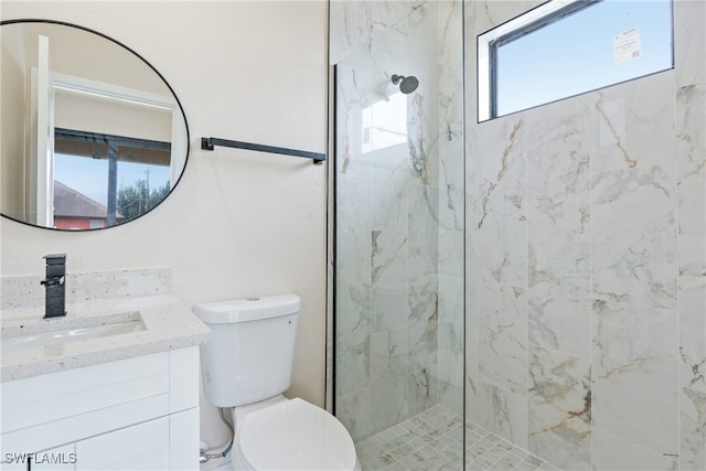 bathroom with vanity, a tile shower, and toilet