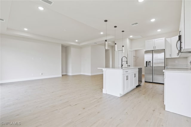 kitchen featuring a kitchen island with sink, light hardwood / wood-style flooring, hanging light fixtures, white cabinetry, and appliances with stainless steel finishes