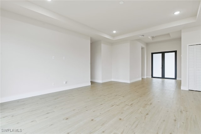 unfurnished room featuring french doors, light hardwood / wood-style floors, and a tray ceiling