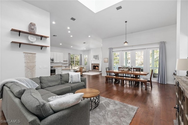 27232 J C Ln, Bonita Springs, FL 34135 - living room featuring a warm lit fireplace, dark wood-style floors, recessed lighting, high vaulted ceiling, and baseboards
