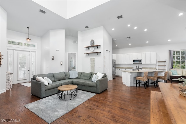 living room featuring a towering ceiling, dark hardwood / wood-style floors, and sink