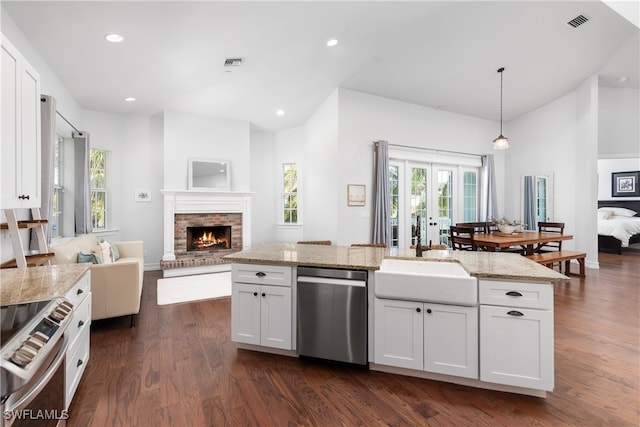 kitchen featuring appliances with stainless steel finishes, hanging light fixtures, white cabinets, dark wood-type flooring, and light stone counters