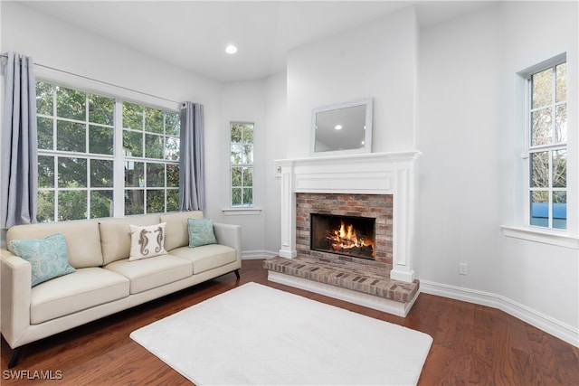 living room with dark wood-type flooring, a wealth of natural light, and a fireplace