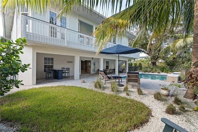 exterior space with a balcony, a lawn, a patio, and a fenced in pool