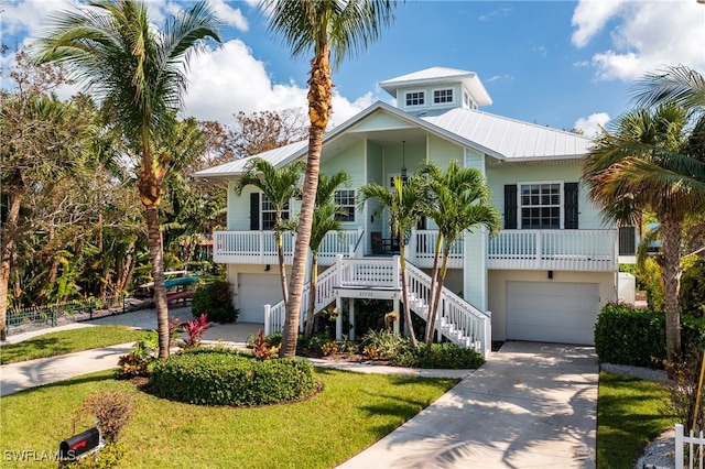 coastal inspired home featuring a front yard, a garage, and a porch