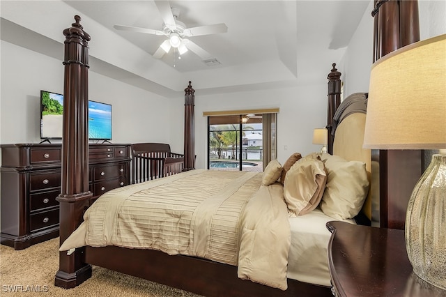 carpeted bedroom with ceiling fan, a raised ceiling, and access to outside