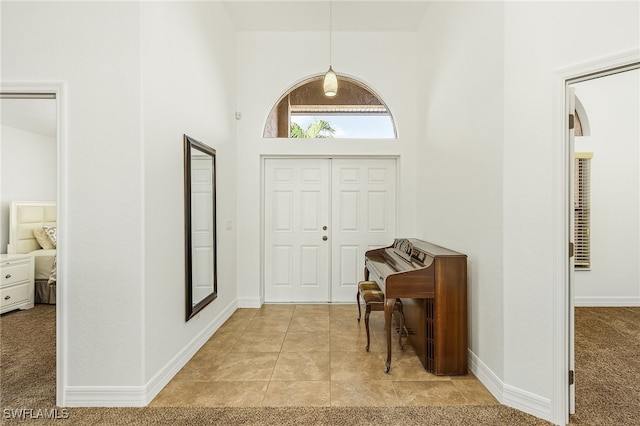 carpeted entryway featuring a towering ceiling