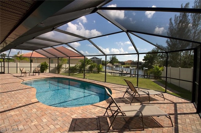 view of pool featuring a patio, a yard, a water view, and glass enclosure