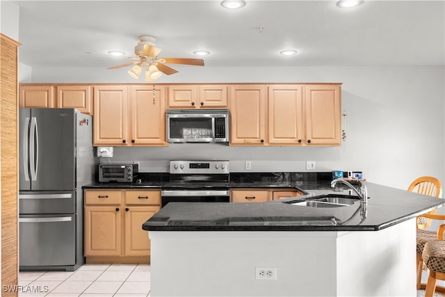 kitchen with light brown cabinetry, kitchen peninsula, appliances with stainless steel finishes, and a kitchen bar