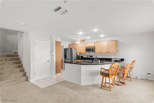 kitchen with light colored carpet, kitchen peninsula, sink, appliances with stainless steel finishes, and light brown cabinetry