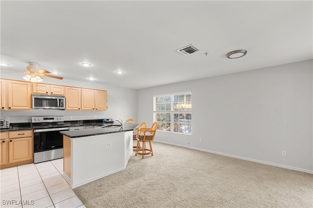 kitchen with stainless steel appliances, light carpet, light brown cabinetry, and sink