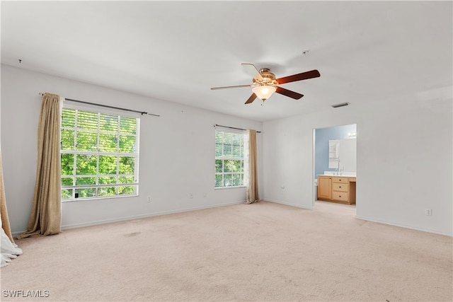 carpeted spare room featuring a wealth of natural light and ceiling fan