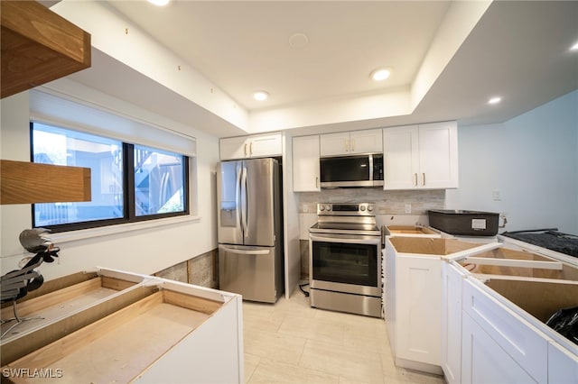 kitchen with recessed lighting, white cabinetry, appliances with stainless steel finishes, backsplash, and a tray ceiling