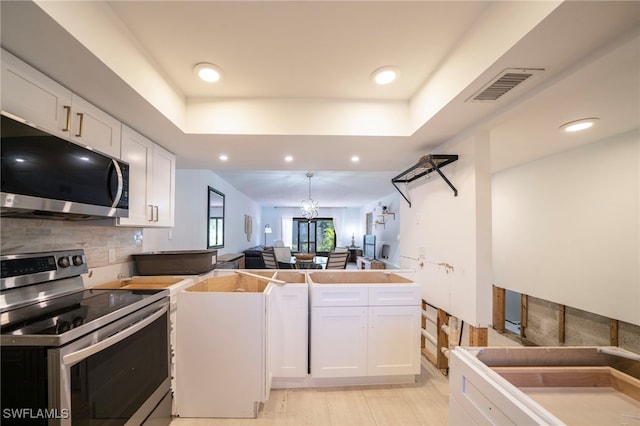 kitchen with visible vents, white cabinets, open floor plan, appliances with stainless steel finishes, and a raised ceiling