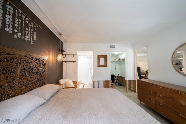 bedroom featuring ensuite bath, a spacious closet, visible vents, and a closet