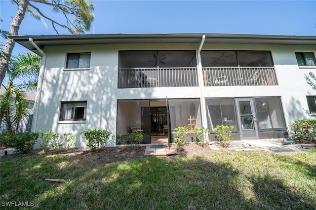 back of house featuring a lawn and stucco siding