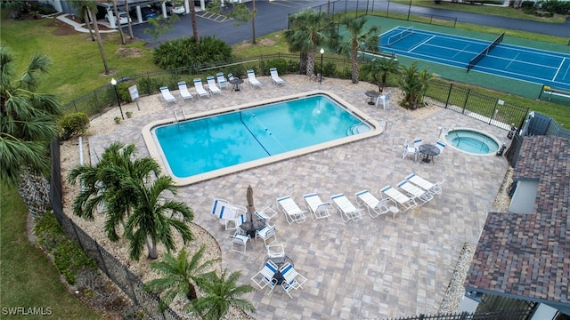 community pool with a patio, fence, and a hot tub