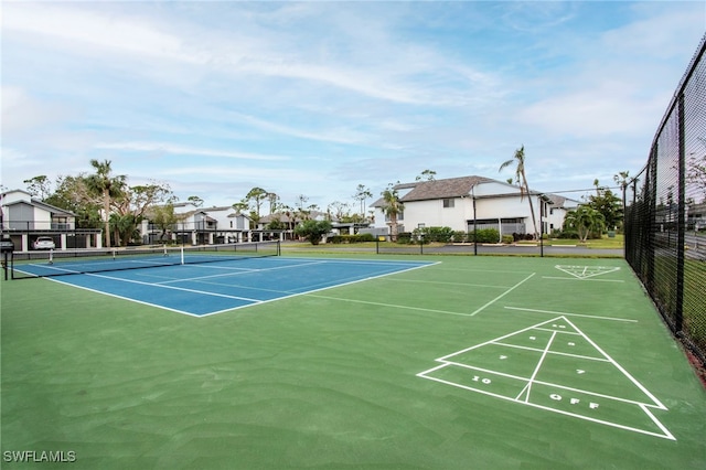 view of tennis court with a residential view, fence, and shuffleboard